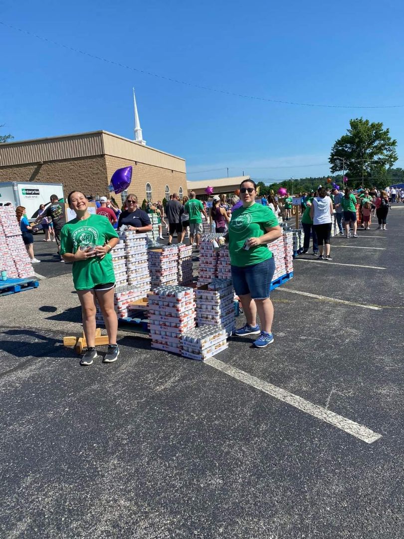 Volunteers pose along side cases of food to be packed